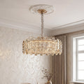 Luxurious gold nordic chandelier featuring a wide drum frame adorned with textured clear crystal prisms suspended in an elegant room.