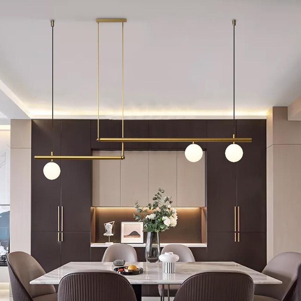 Gold linear pendant light above dining table with warm ambient lighting.
