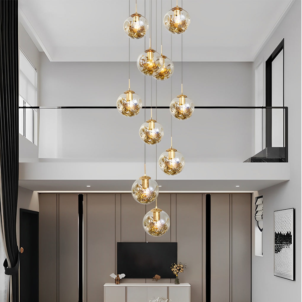 Gold staircase chandelier with a luxurious design, providing warm light in a high-ceiling hallway.