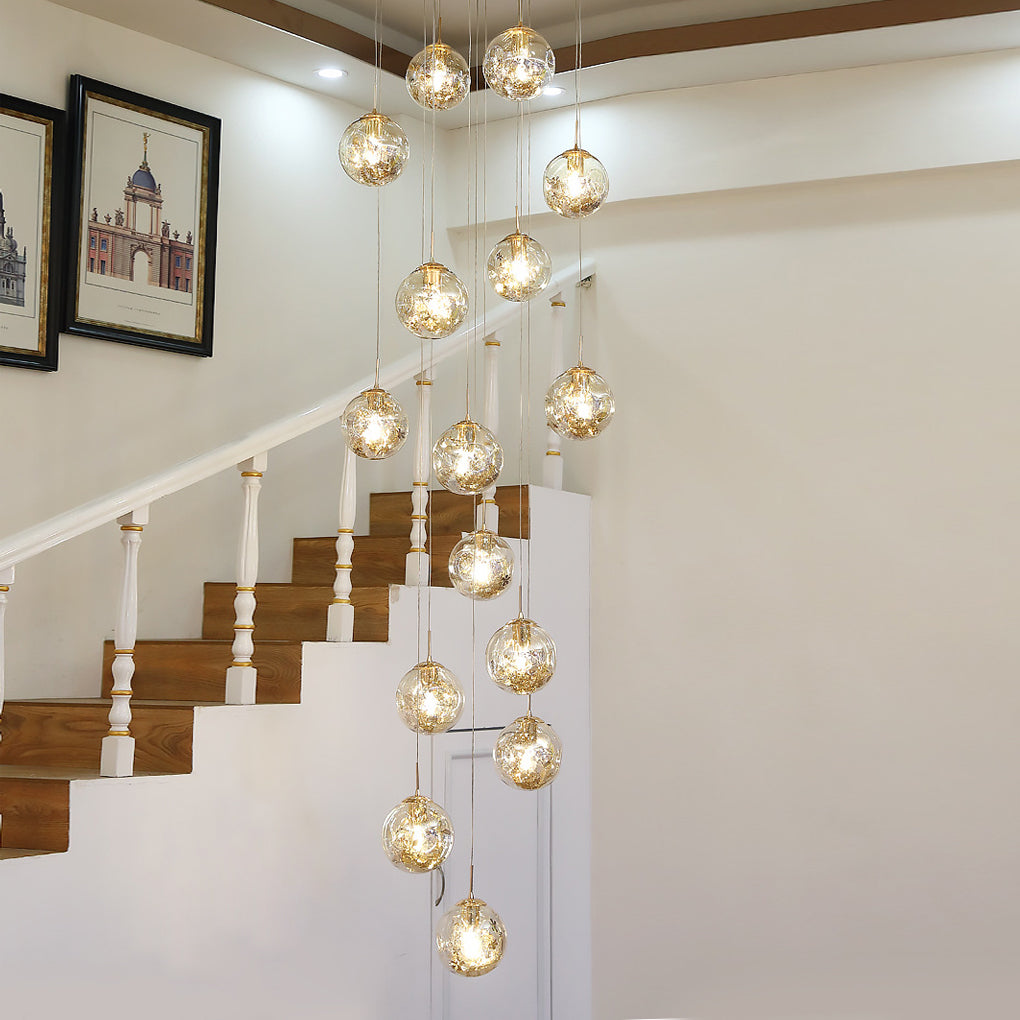 Gold staircase chandelier with a modern design, illuminating a white staircase and living area.