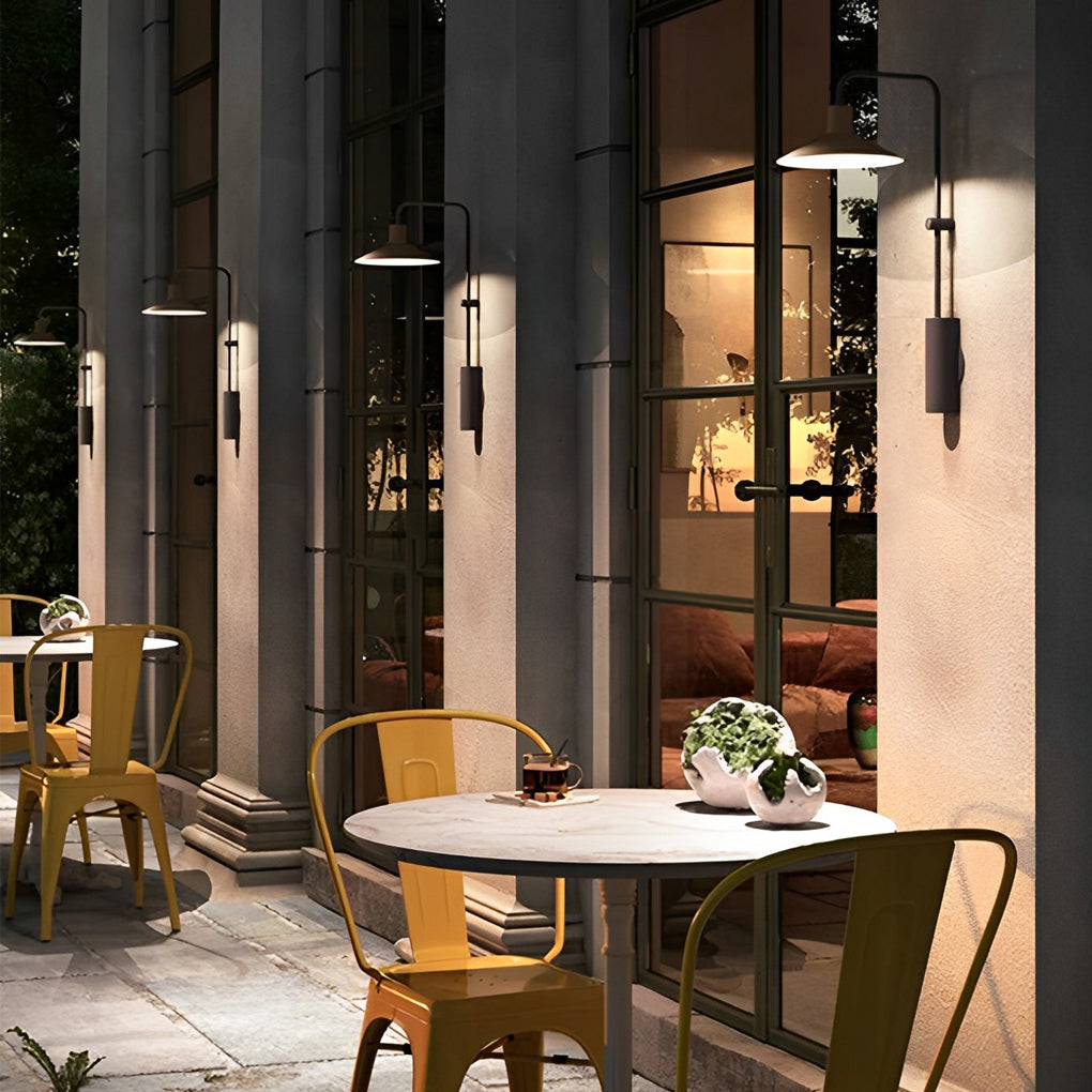Gooseneck wall lamp illuminating a café-style outdoor dining area with warm, welcoming ambient light.