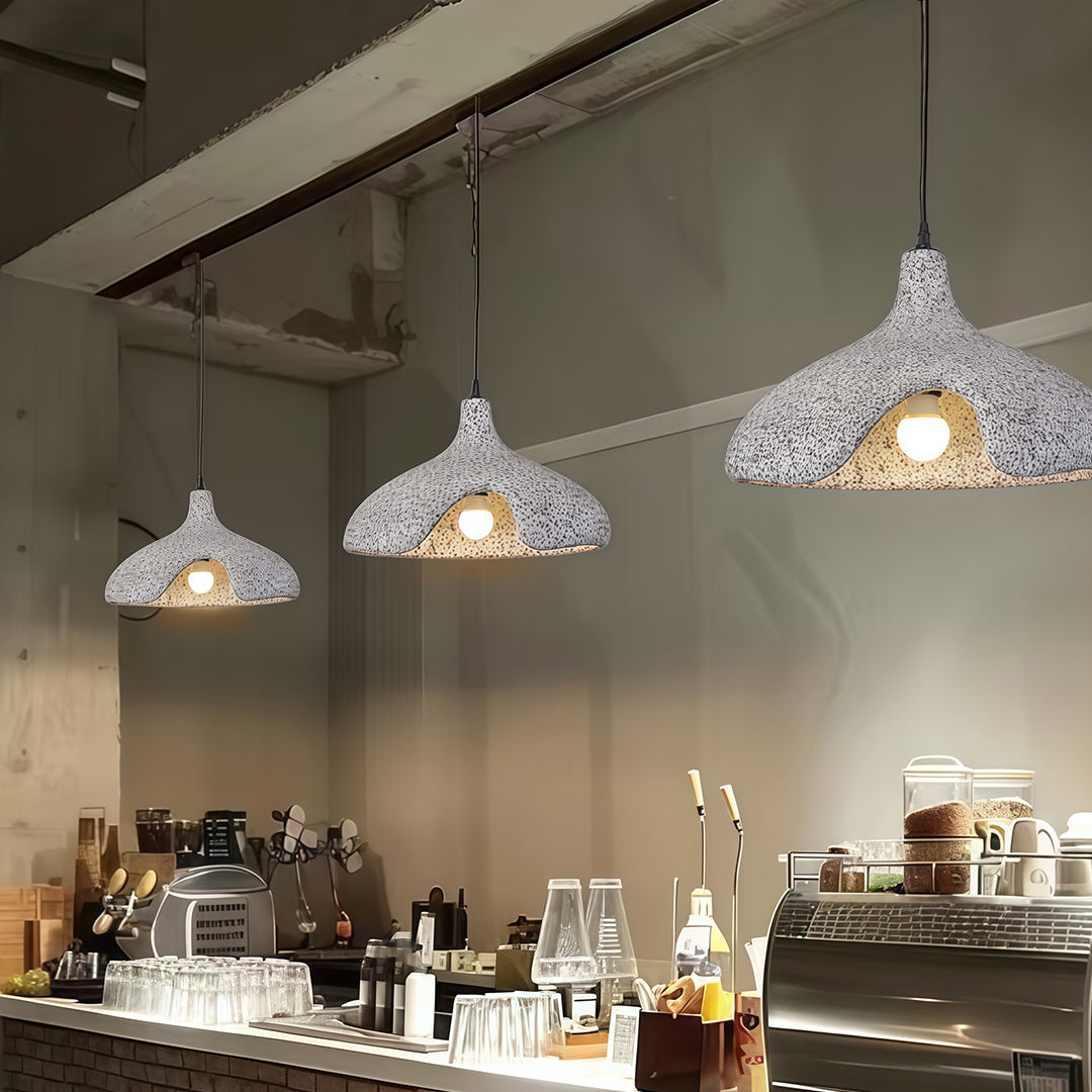 Gray cement pendant light illuminating modern café interior with wooden tables and warm tone.
