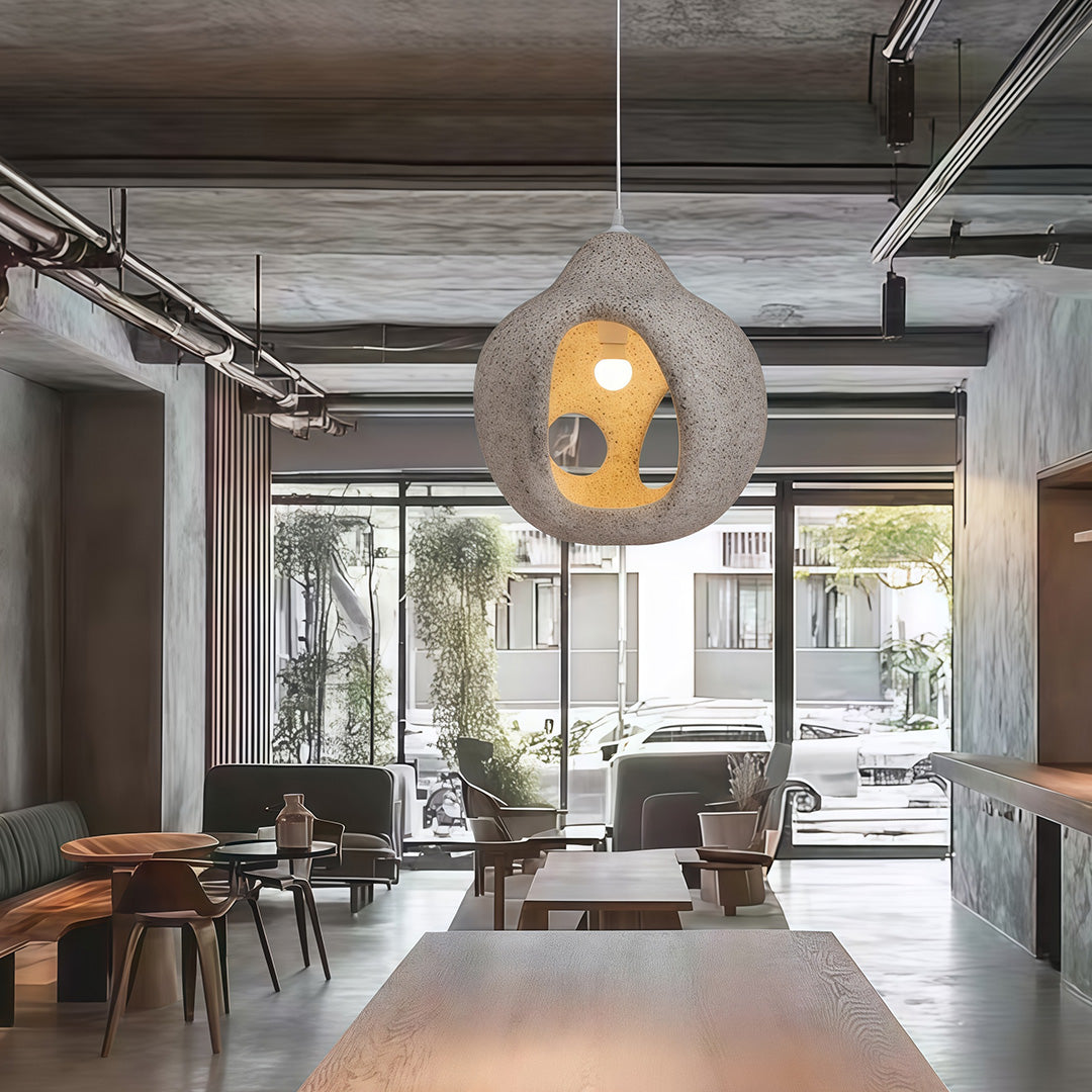 Nordic wabi sabi pendant light with gray textured shell hanging over modern living area with natural light.