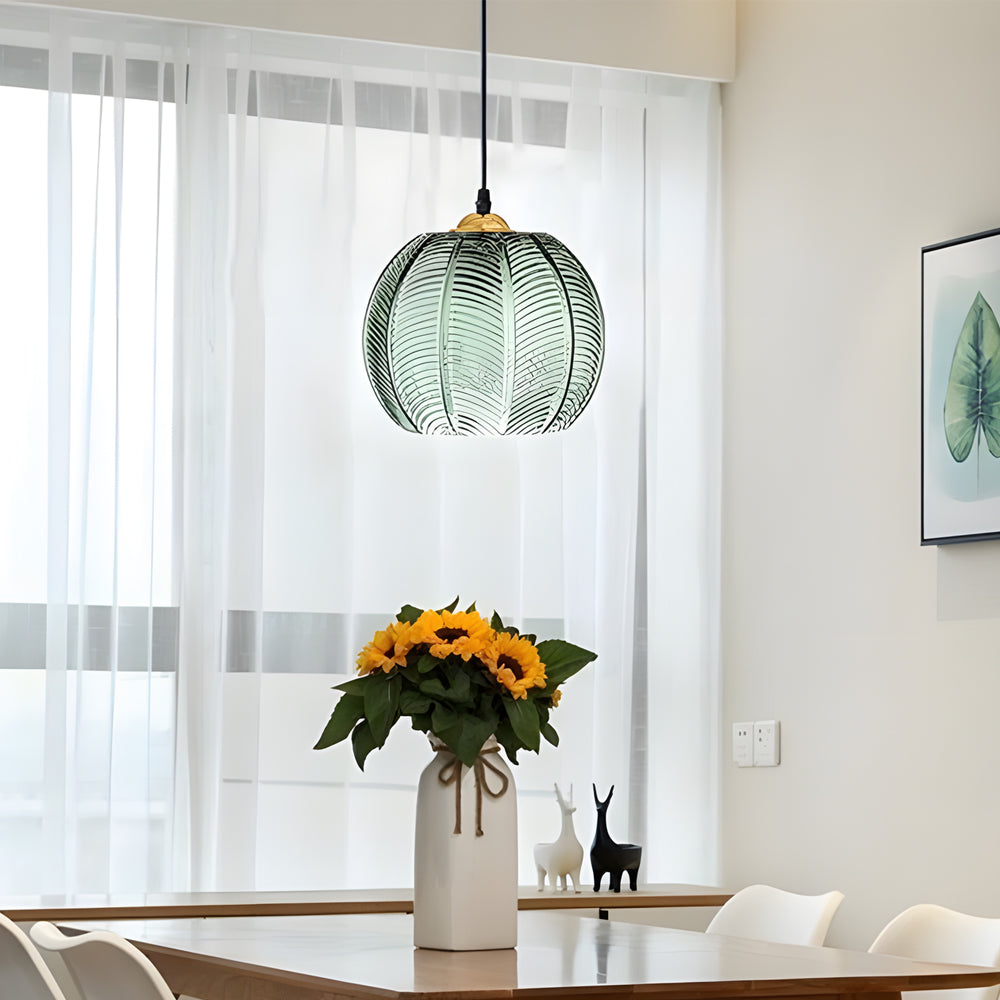 Green glass pendant light installed near a window providing soft natural and ambient light.