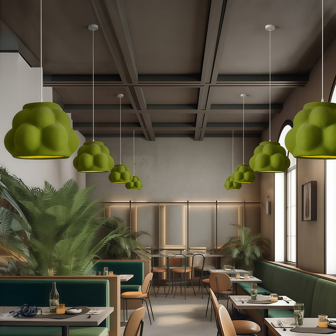 Green single pendant light fixture in modern café interior with plants and warm atmosphere.