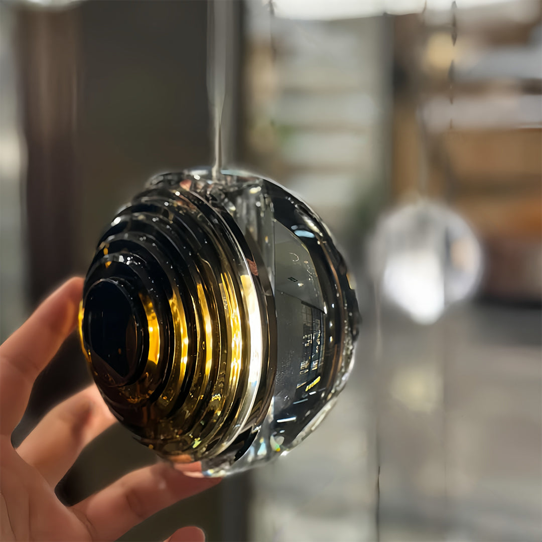 Hand holding a metal pendant light with a smoked glass sphere, showcasing its unique and elegant design.