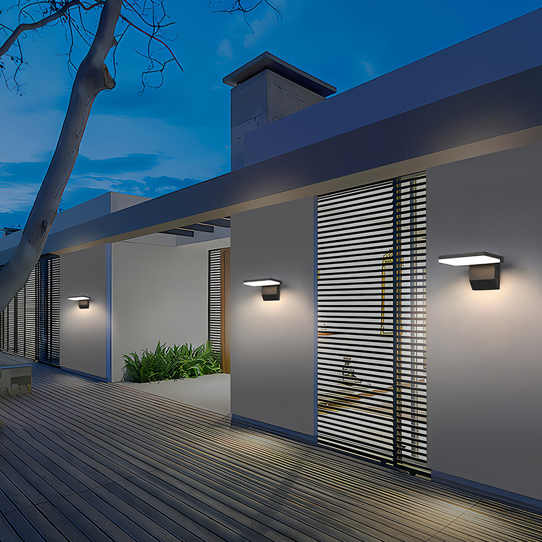 Industrial wall lights illuminating modern residential courtyard with decorative patterned walls at dusk