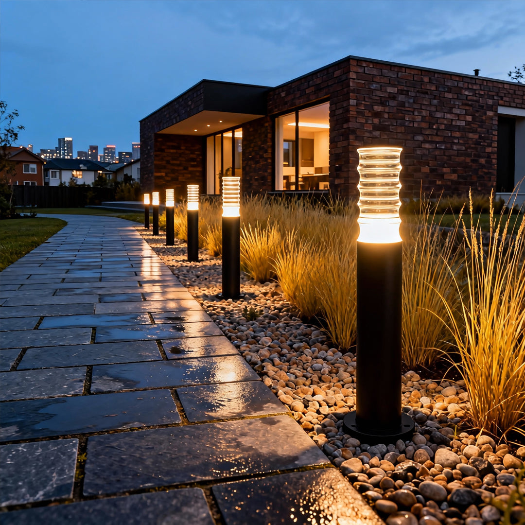 Multiple landscape lighting bollards placed along a modern house walkway, offering warm and balanced outdoor illumination.