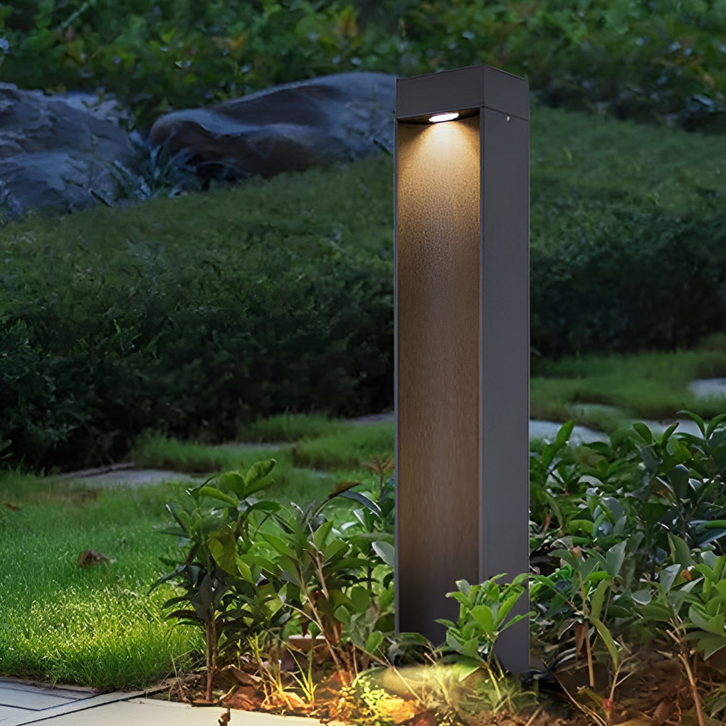 LED bollard light used for landscape lighting near shrubs and plants.