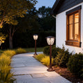LED fence bollard light brightening stone walkway leading to white home entrance at dusk