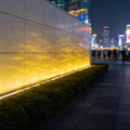 LED flood light fixtures creating warm ripple lighting effect on modern commercial building wall.