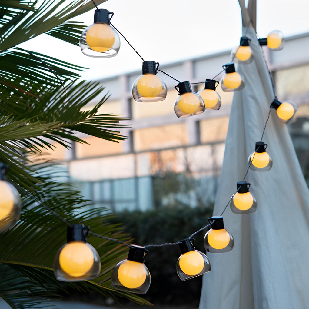 LED globe string lights draped along a patio umbrella and railing, providing decorative outdoor lighting for evening use.