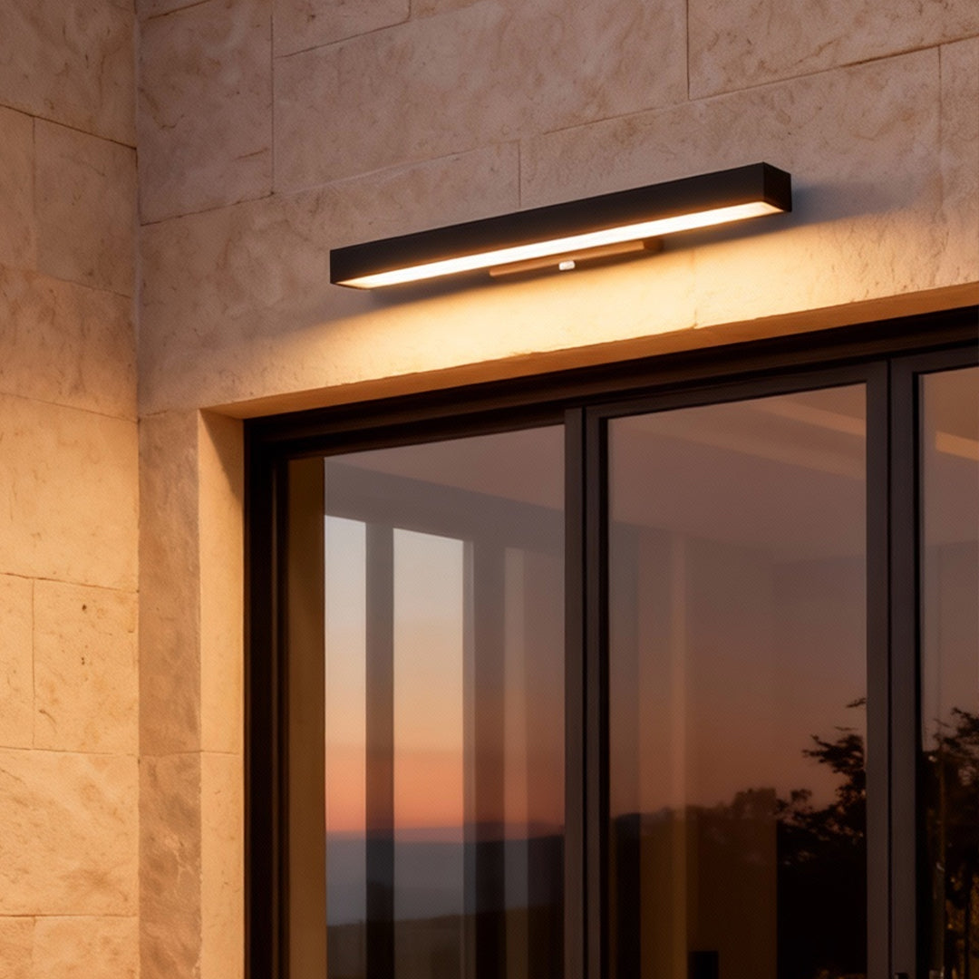 Slim LED linear wall light positioned above glass doors, creating soft ambient light and a refined modern exterior appearance.