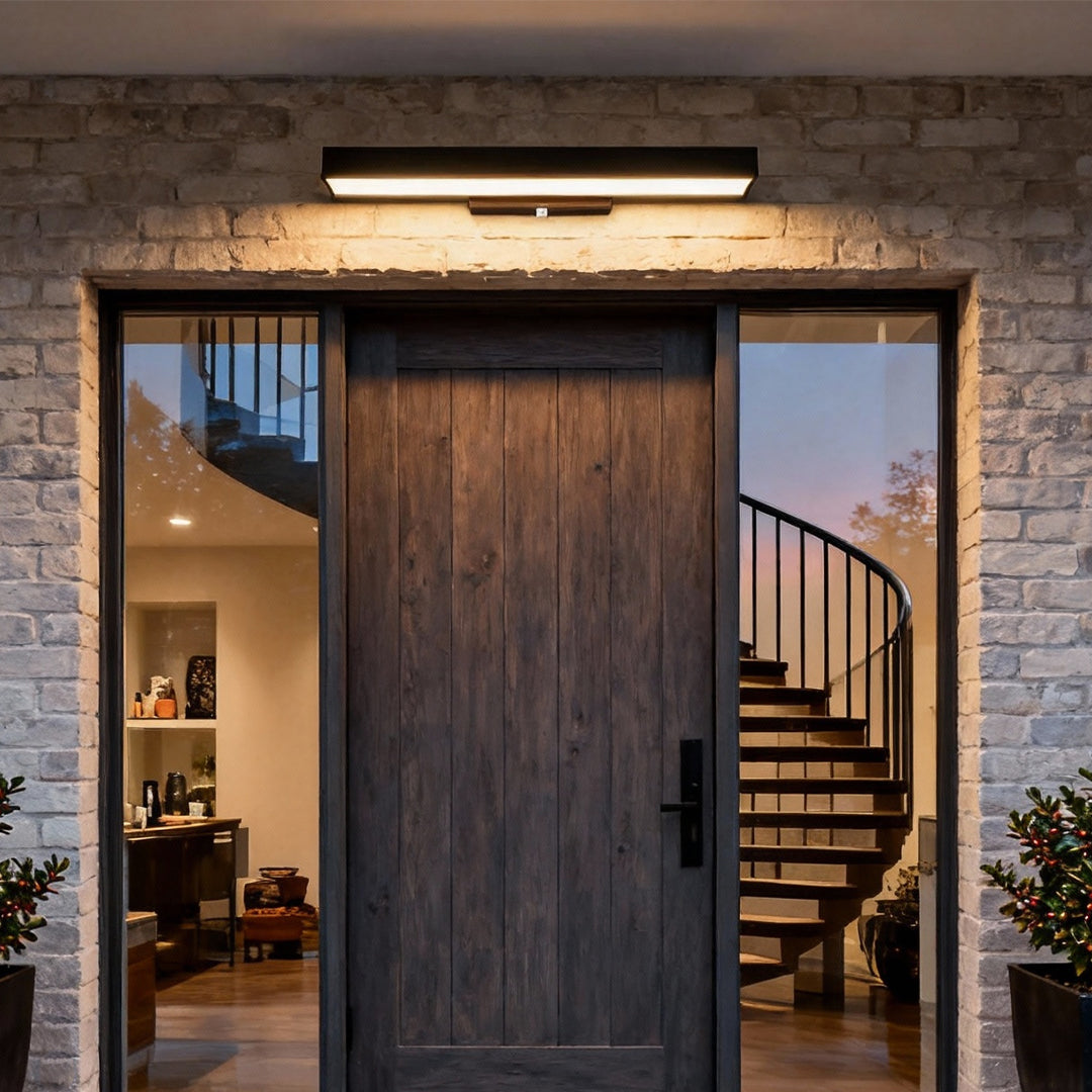 Contemporary LED linear wall light mounted over a stone entryway, providing even horizontal lighting for a modern architectural facade.