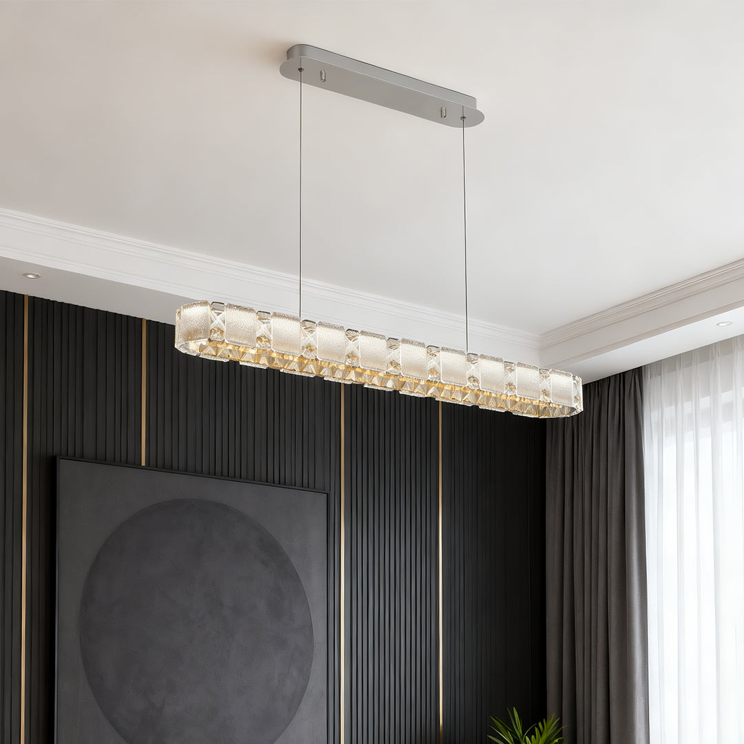 Long linear chrome chandelier illuminating modern hallway entrance with crystal accent lighting.
