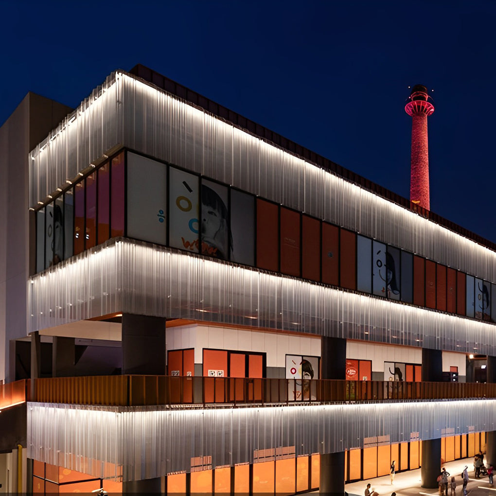 Linear LED wall washer illuminating a modern building entrance with vertical metal paneling.