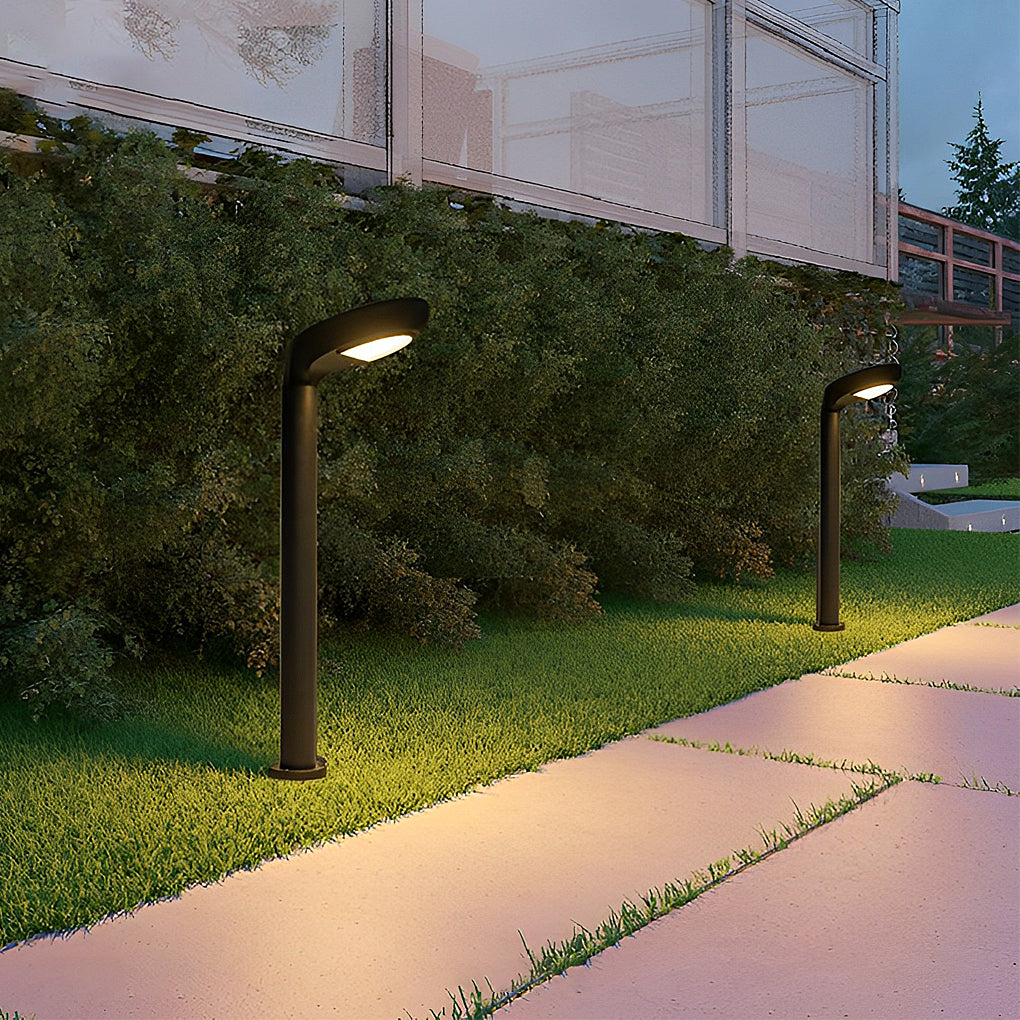 Low profile curved bollard light placed along a hedge-lined walkway.