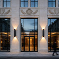 Luxury commercial entrance illuminated by black up and down wall lights with warm LED beams.