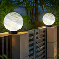 Globe pillar lights with marble texture illuminating modern garden pathway at dusk.