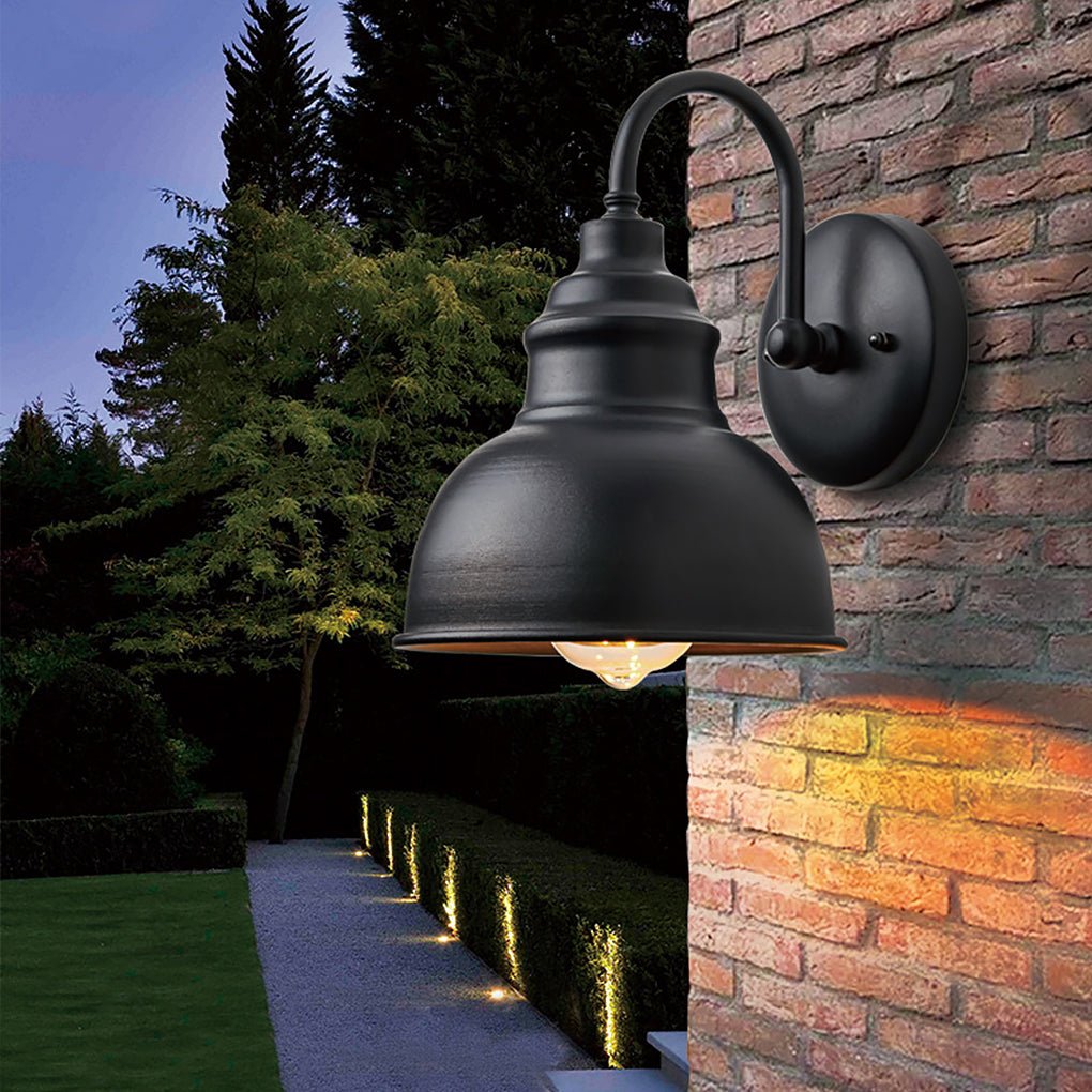 Close-up of a matte black gooseneck light on a brick wall, casting focused downward light along an outdoor pathway.