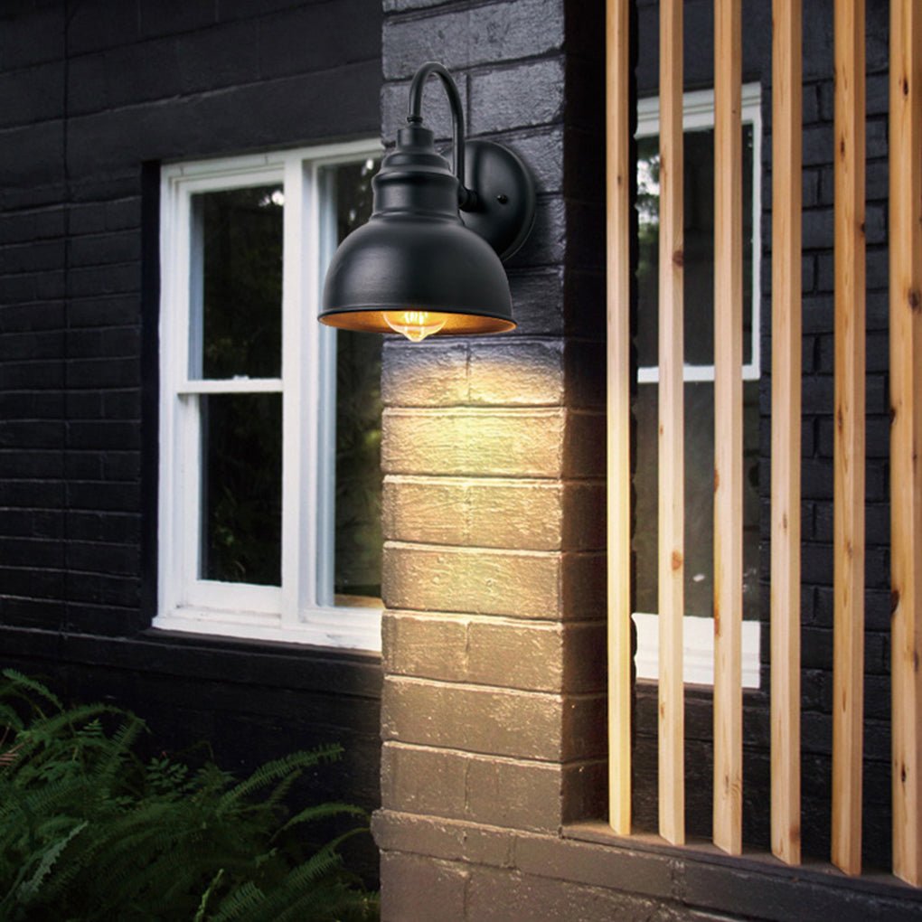 Matte black gooseneck light mounted near a window on a dark exterior wall, highlighting architectural details at night.