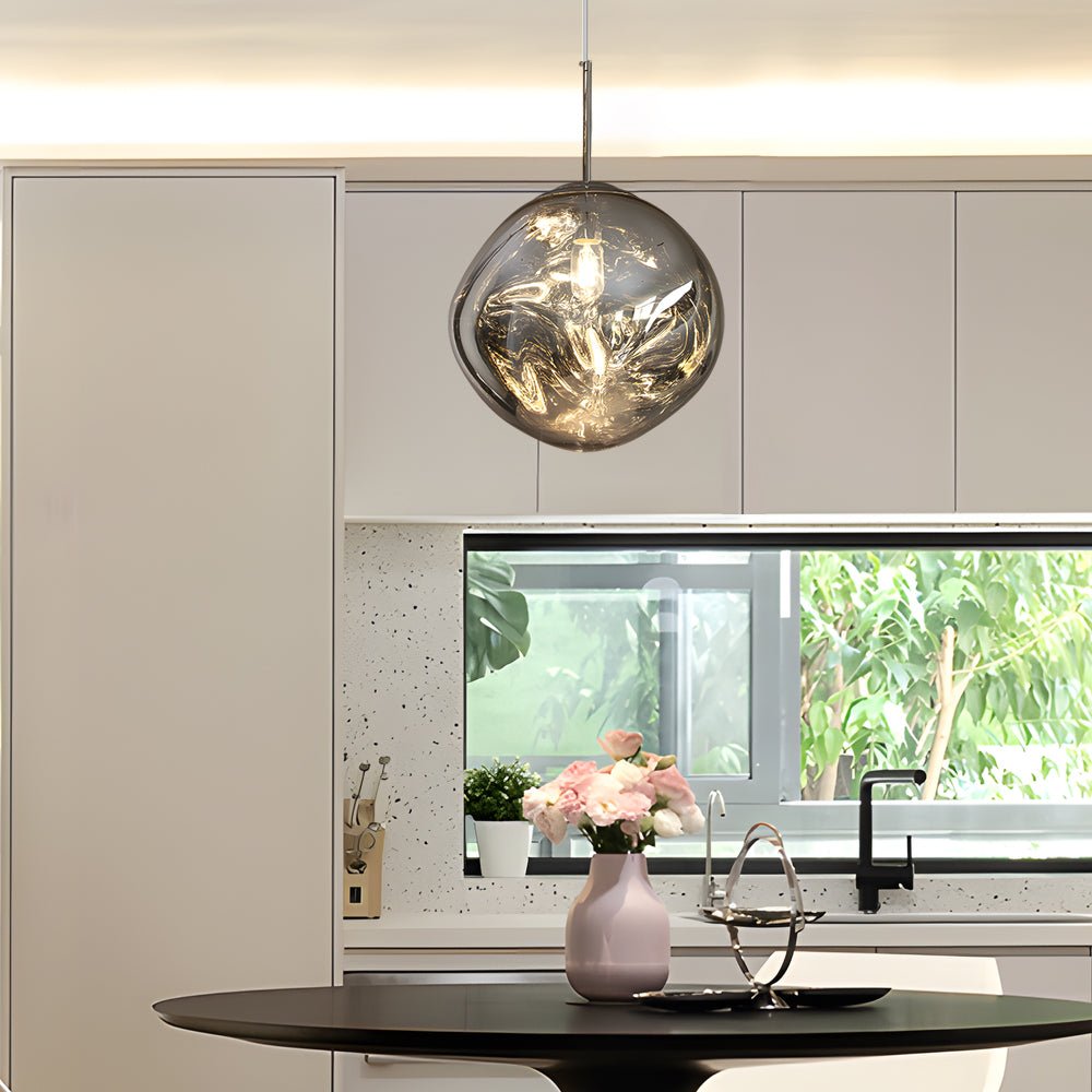 Single melt LED pendant light centered above a dining table, reflecting natural light and interior details.