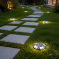 Metal deck lights illuminating a modern garden pathway with warm ambient glow.