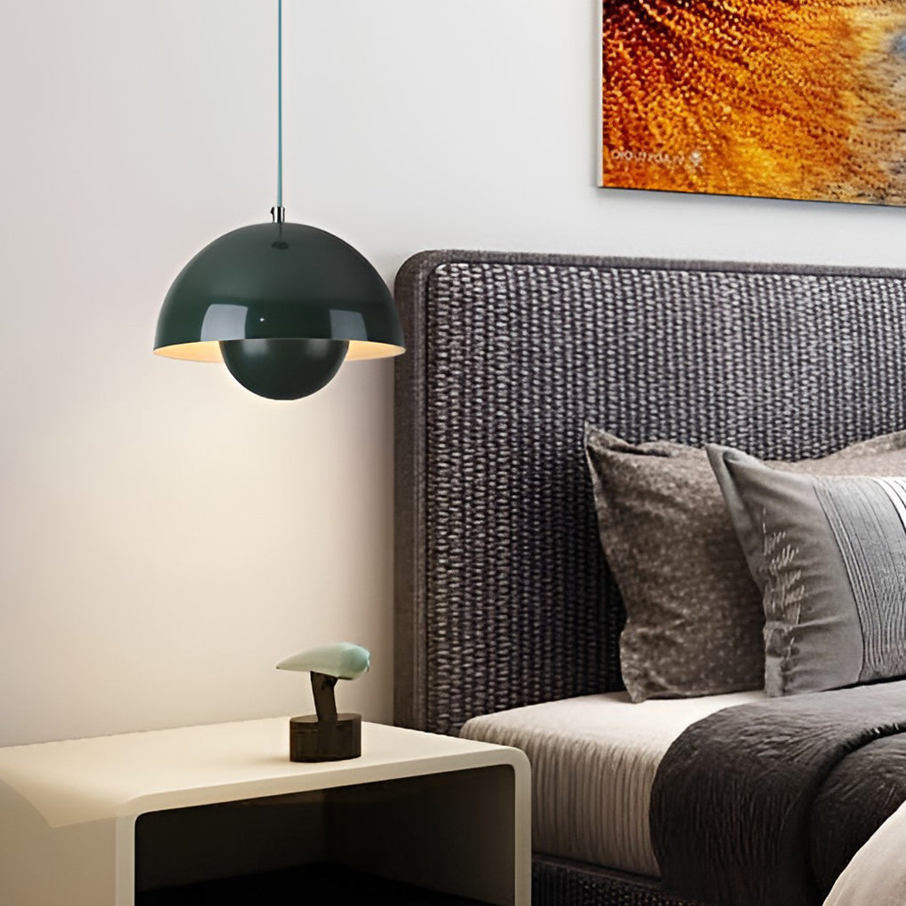 Metal dome pendant light in dark green, illuminating cozy bedroom with gray headboard.