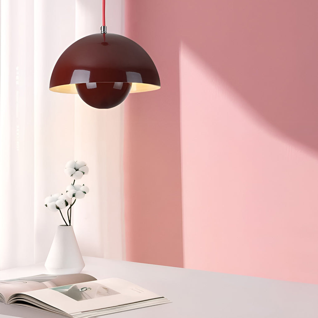 Metal dome pendant light in maroon, casting warm light on pink accent wall.