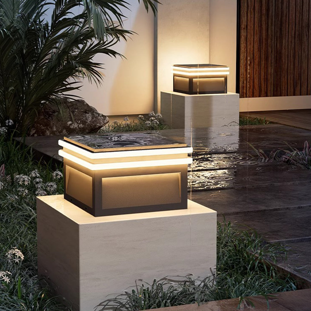 Metal pillar lights in a garden setting, creating a modern and inviting outdoor atmosphere.