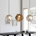 Modern metal shade pendant light with geometric perforated design hanging above a dining table in a bright contemporary interior.