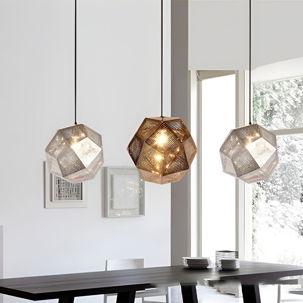 Modern metal shade pendant light with geometric perforated design hanging above a dining table in a bright contemporary interior.