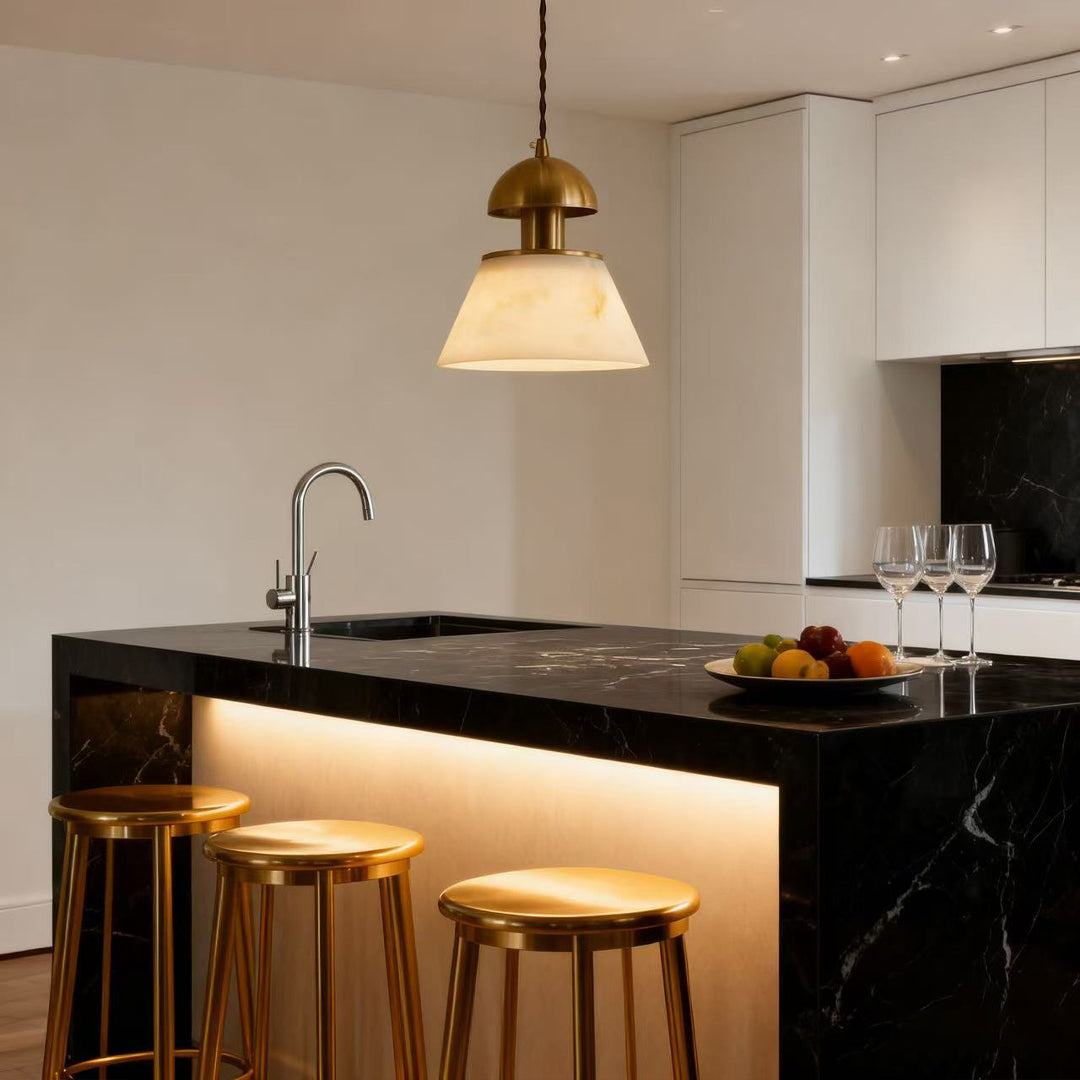 Metallic pendant lights illuminating kitchen island with warm glow above black countertop and wooden bar stools