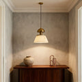 Metallic pendant lights creating focal point in minimalist alcove above wooden cabinet with textured concrete walls