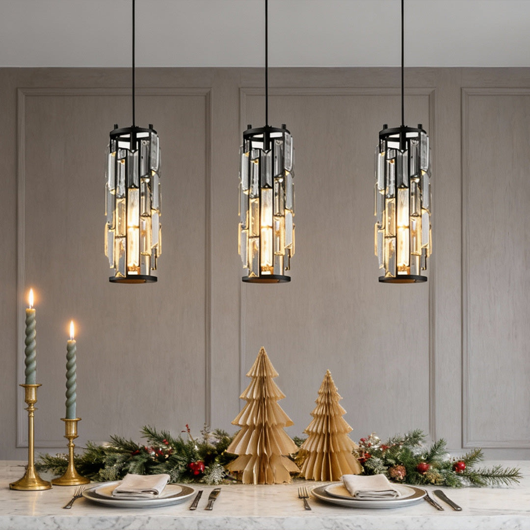 Three mini crystal pendant lights hanging over a dining table with elegant holiday decor.