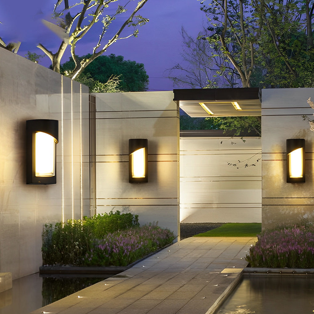 Black outdoor wall light with minimalist design on white wall beside wooden door.