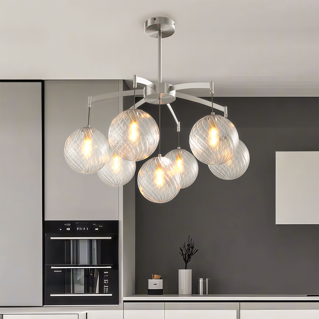 Minimalist modern glass ball chandelier with a gold finish, suspended in a bright and airy living space.