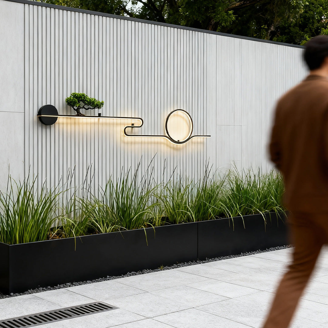 Minimalist outdoor wall lights installed along a garden pathway wall at dusk.
