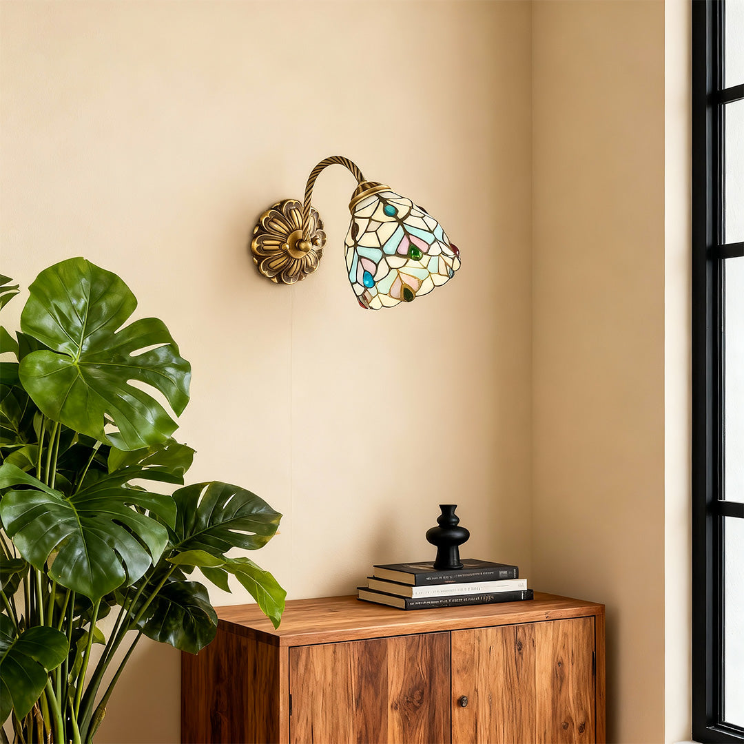 Minimalist stained glass wall sconce lighting featuring glass shade chandelier design illuminating entryway with green plant accent.