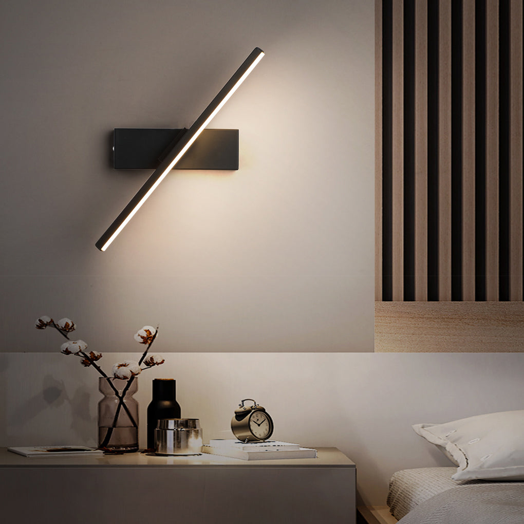 Minimalist swivel wall light with a black and white design, mounted above a bedside table with decorative items.