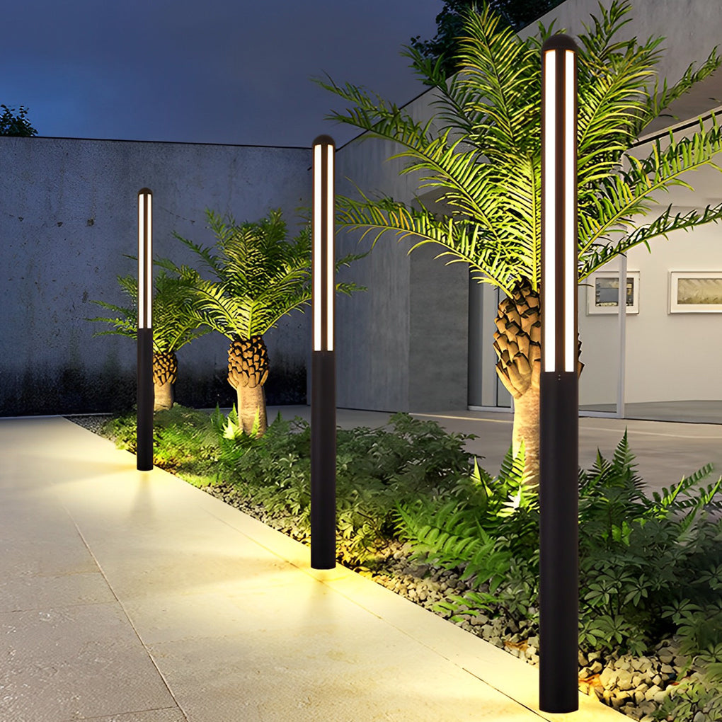 Tall garden bollard light with minimalist design beside pool and lounge area.