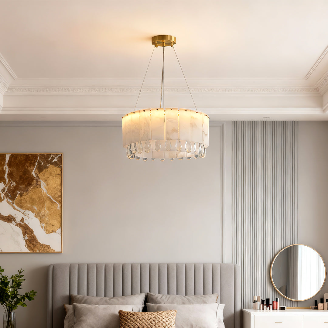 Warm modern brass chandelier suspended above a modern bed with wall art.