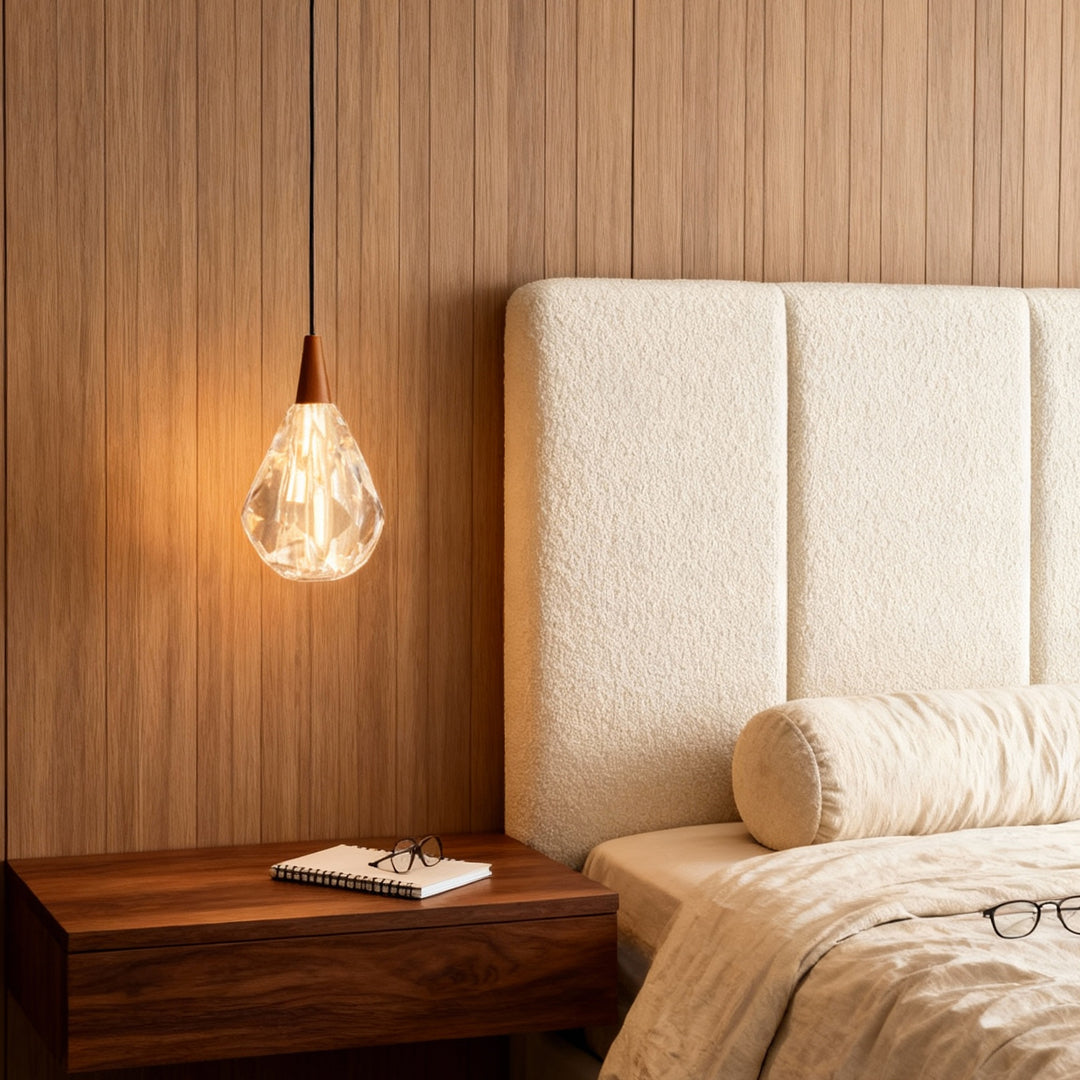 Modern crystal pendant lighting creating ambient lighting beside bed with natural wood slat wall and neutral upholstery