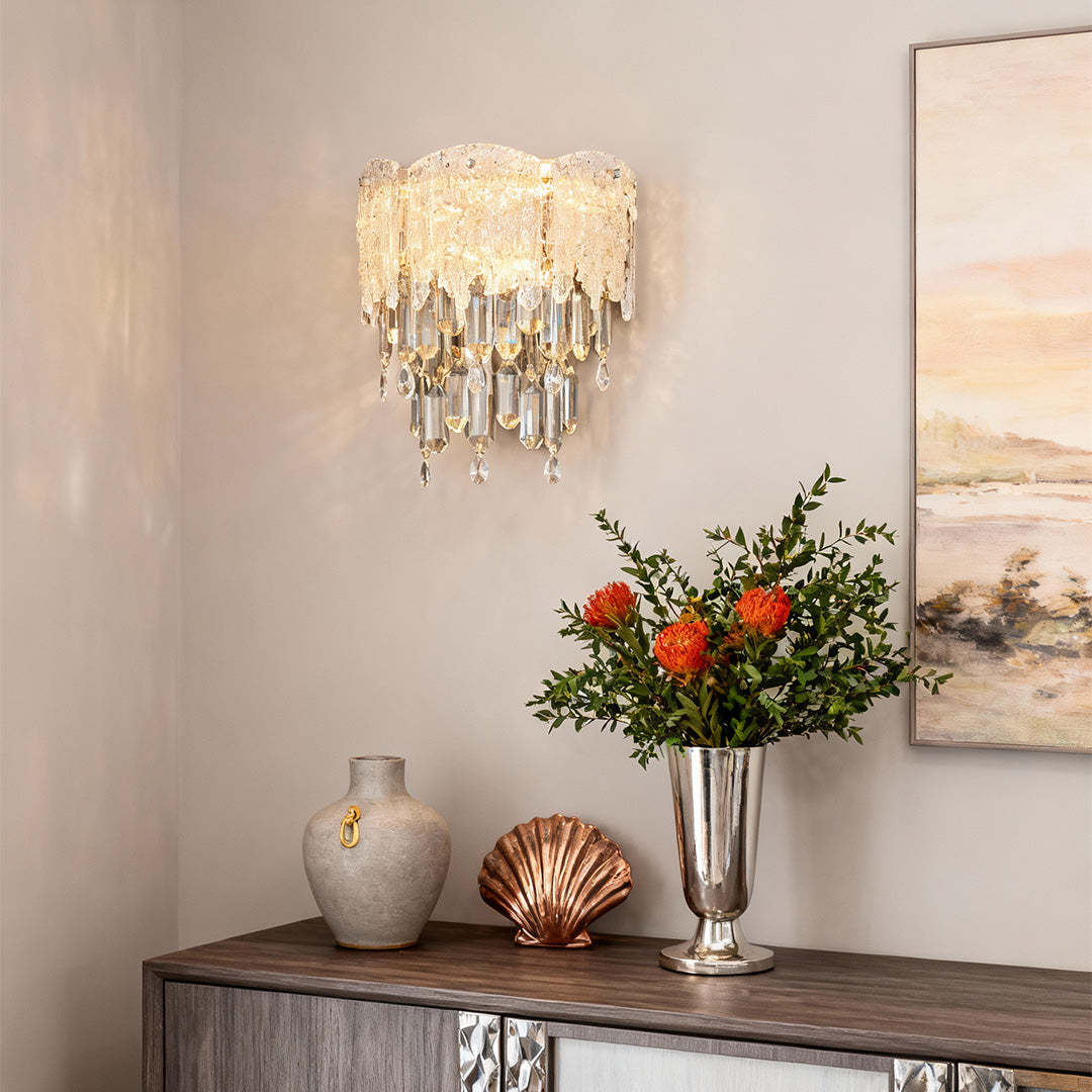 Modern living room decorated with gold crystal wall sconce lighting and flowers.