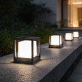 Garden pedestal lights with modern black frame illuminating poolside pathway at night.