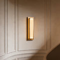 Modern gold wall light fixture glowing on a classic curved paneled wall in a luxury home space.