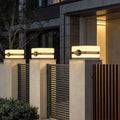 Modern house pillar lights installed along a sleek metal fence with stone pillars at a residential entrance.