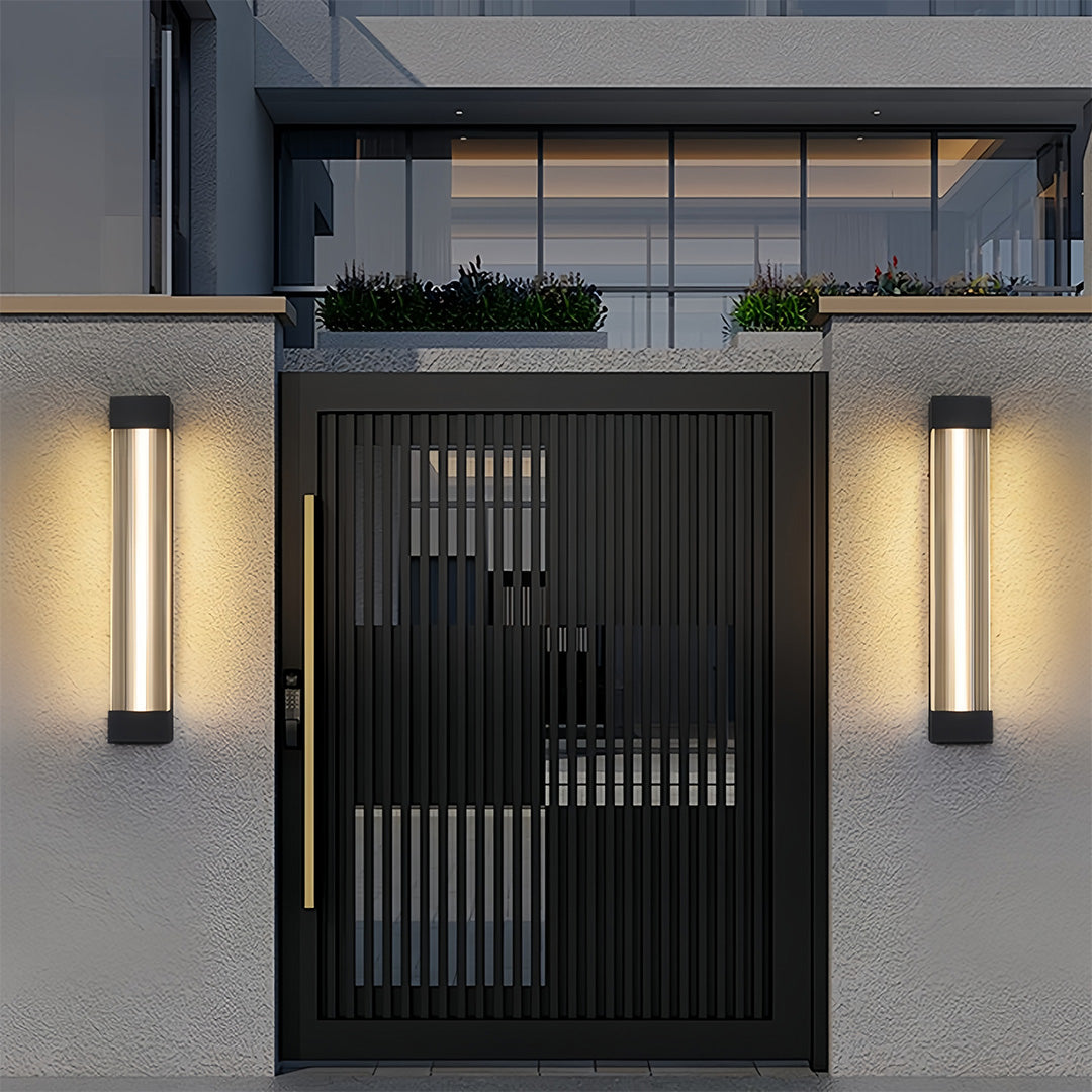 Modern linear outdoor sconce fixtures illuminating the front gate pillars of a contemporary home.