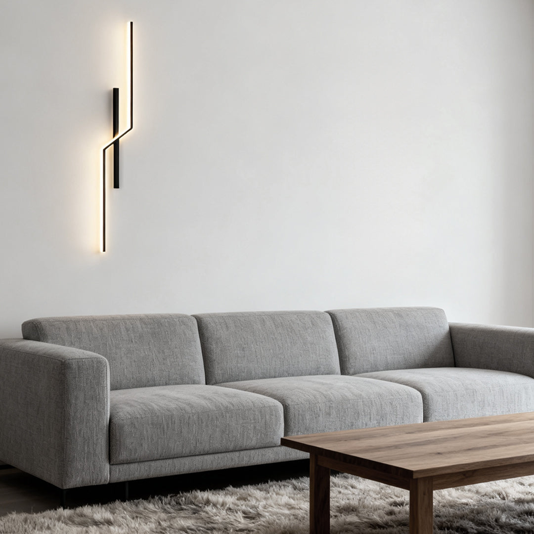 Slim modern linear wall sconce used as vertical decorative lighting beside sofa in modern living room.