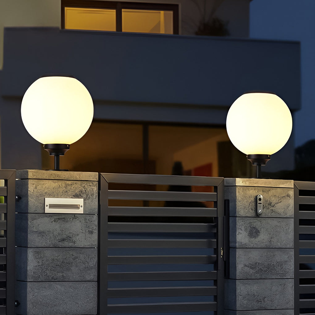Modern outdoor gate pillar light with spherical design, providing warm illumination at the entrance of a residential building.